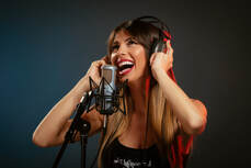 Mujer feliz con audífonos y micrófono cantando